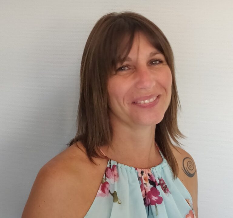 Femme souriante avec un tatouage en spirale portant un haut floral